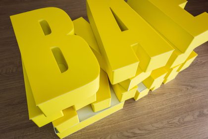Three-dimensional letters made of plastic for signage.Production of outdoor advertising in production.Three-dimensional yellow letters are lying on the table. Three-dimensional letters made of plastic for signage.Production of outdoor advertising in production.Three-dimensional yellow letters are lying on the table.